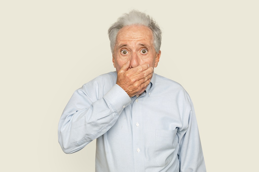 Shocked senior man with hand covering his mouth